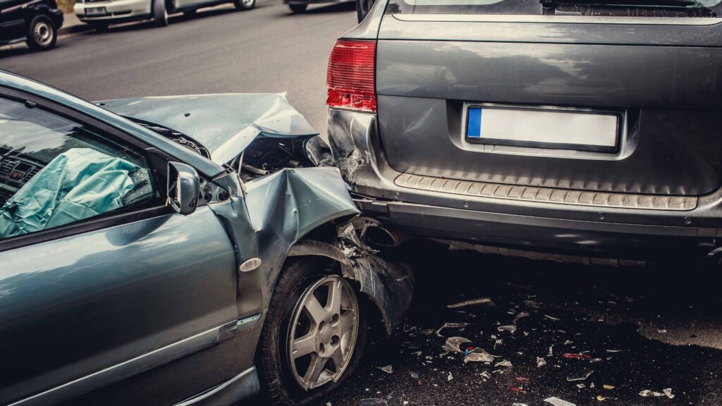 A rear-end collision between two cars, with deployed airbags and debris scattered on the road, showcasing the type of accident handled by a Gulfport Rear-End Accident Attorney.