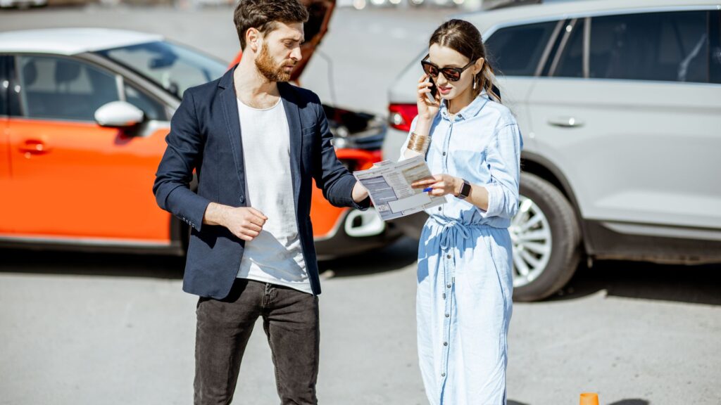 A man and a woman exchanging information after a car accident, illustrating the impact of a car accident on a driver's record.